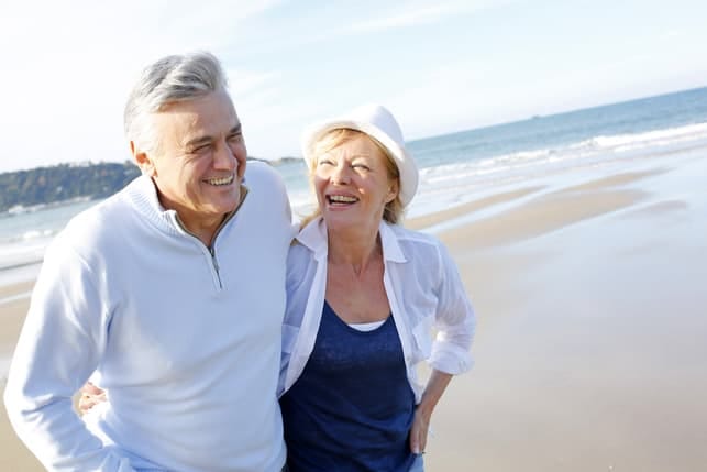 a happy couple over 50 having a walk on a beach
