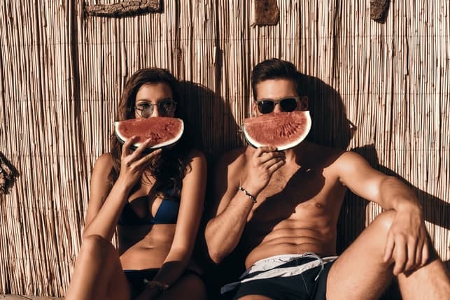 a fit couple is enjoying watermelon together