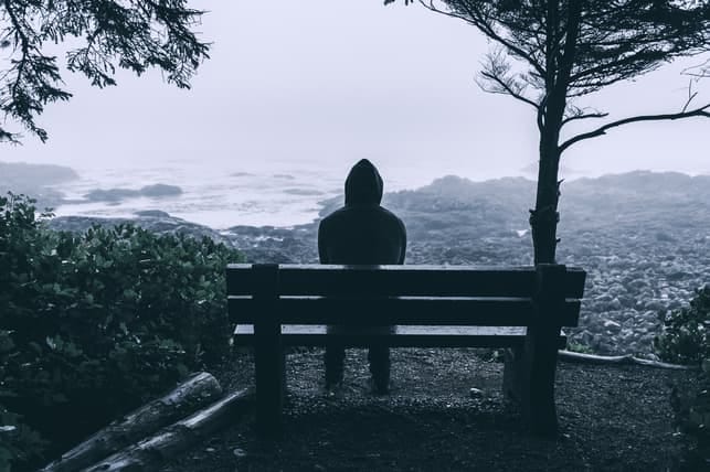 a lonely man sitting on a bench