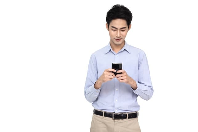 an attractive young Asian man is using his smartphone