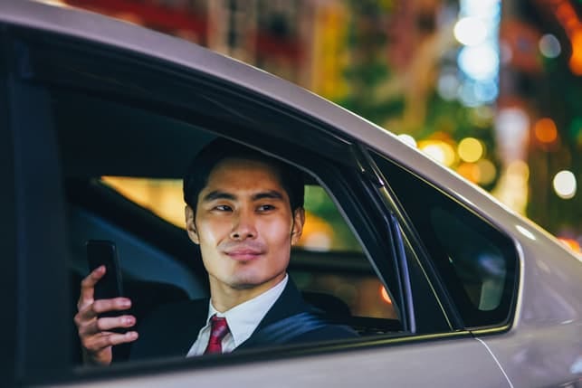an asian man in a suit sitting in his car