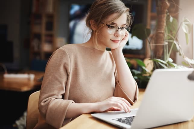 a young woman is using her laptop while smiling