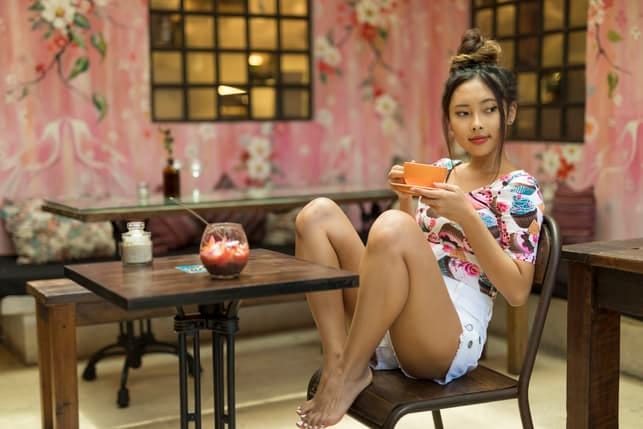 an attractive asian woman drinking tea in a cafe
