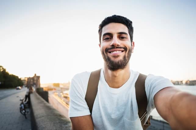 a portrait of a young man taking selfie outdoors