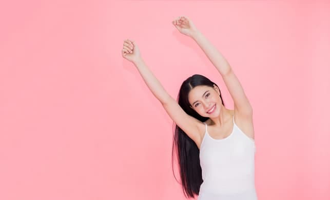 a young happy asian woman posing on a pink background