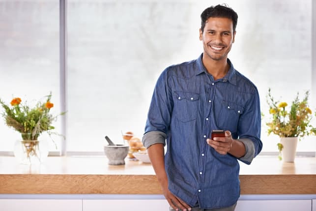 an attractive man in a blue shirt posing and smiling indoors