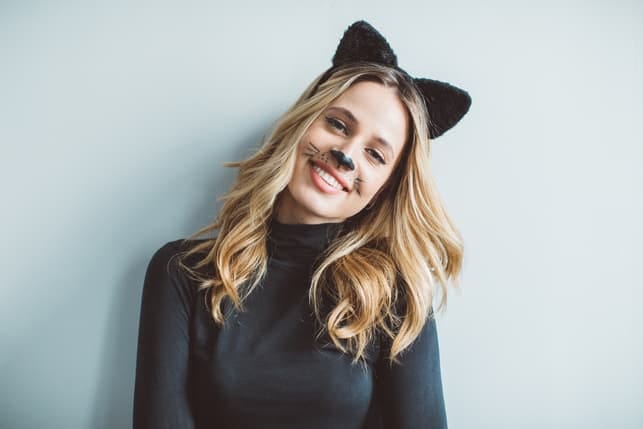 a young blonde woman with cat carnival makeup and cat ears is smiling
