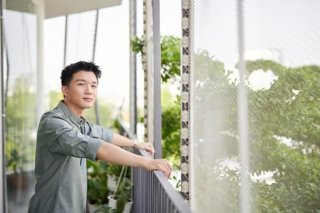 a young asian man posing on his balcony
