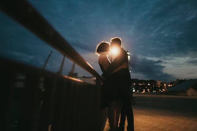 a romantic couple kissing outdoors in the evening