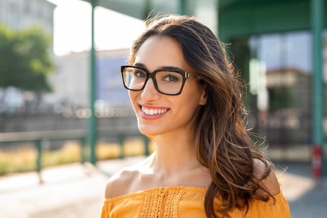 a portrait of an attractive young woman in glasses taken outdoors