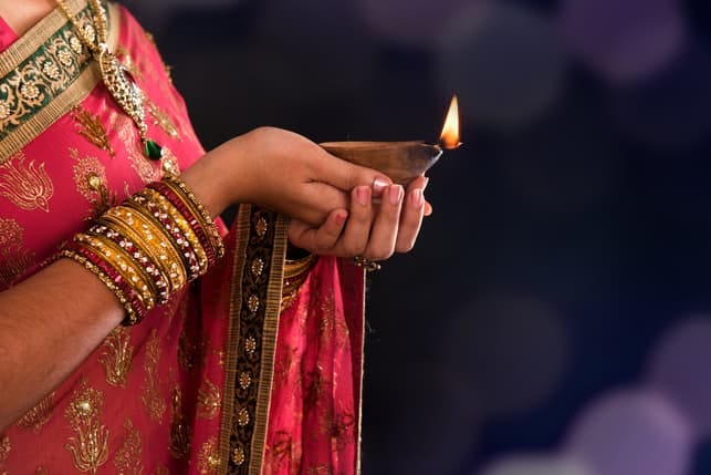 hands of an indian girl holding a candle