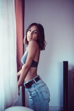 an attractive tanned woman posing in her bedroom