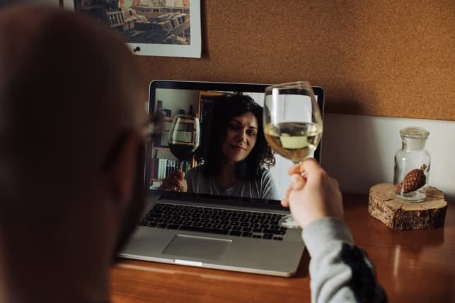 a couple drinking wine and talking via video call