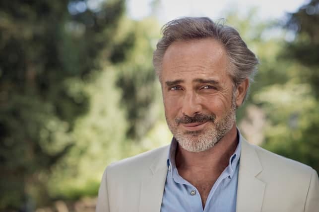 an attractive mature man is smiling outdoors