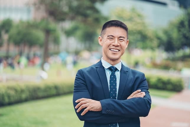 an asian man in a suit laughing