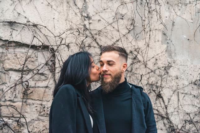 a woman kissing her boyfriend’s cheek