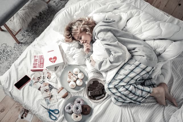 a woman relaxing with cookies and candies on her bed