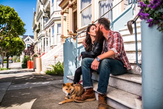 a couple kissing when walking a dog