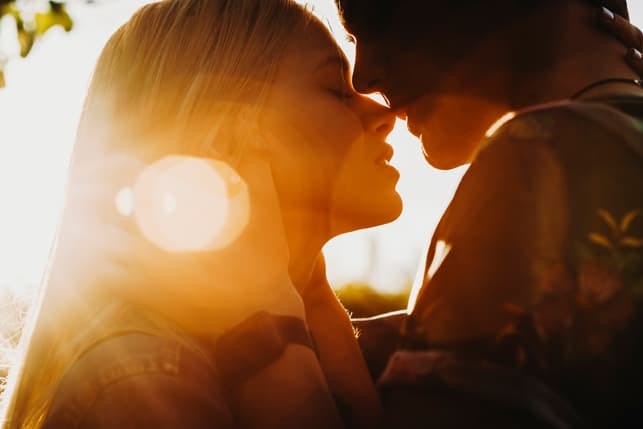 a couple kissing while enjoying a sunset