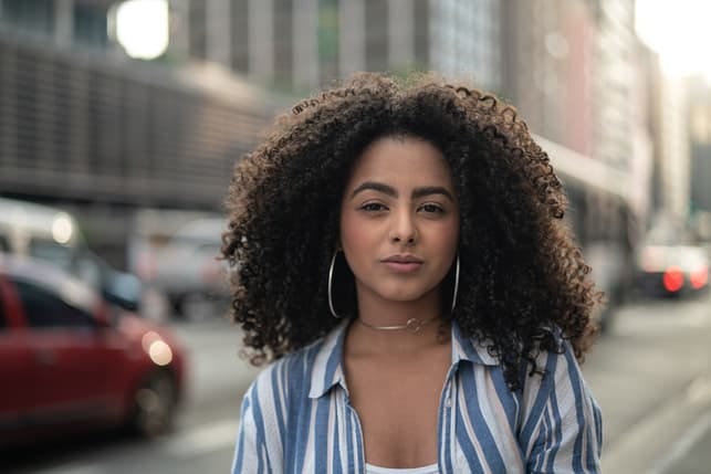 a young girl with curly hair posing in a city