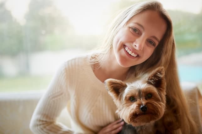 a young blonde woman with a dog is smiling