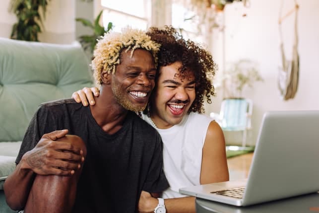 a black gay couple using their laptop together and having fun
