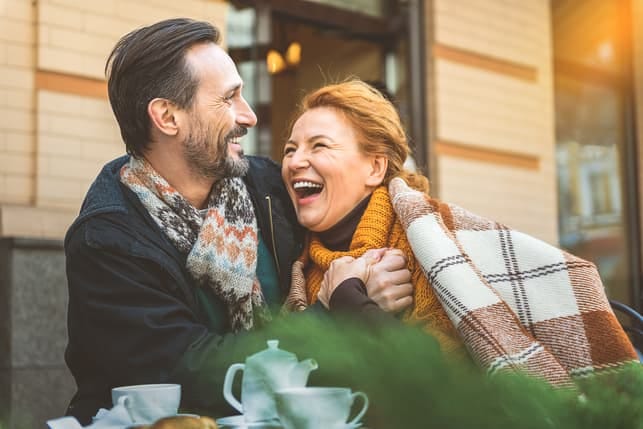 a couple over 50 is having fun together while having lunch at a cafe