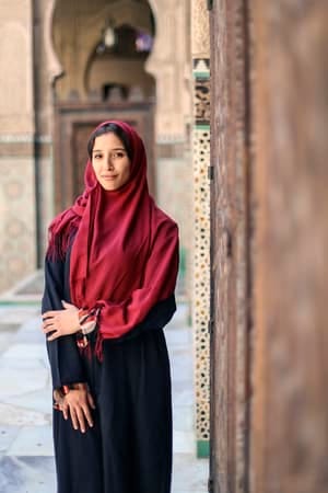 an oriental muslim woman posing outdoors close to an old building
